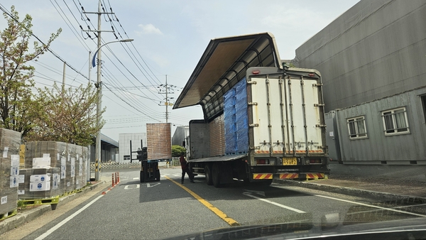 ▲ OKF 대형차량(윙카)가 무단으로 주차해 물품을 상하차하는 가운데 지게차가 중앙선을 침범하고 있다. 왼쪽에는 인도에 물품을 마구잡이로 적치돼있으며 인도가 파손된 흔적도 보이고 있다. ⓒ영남경제 자료